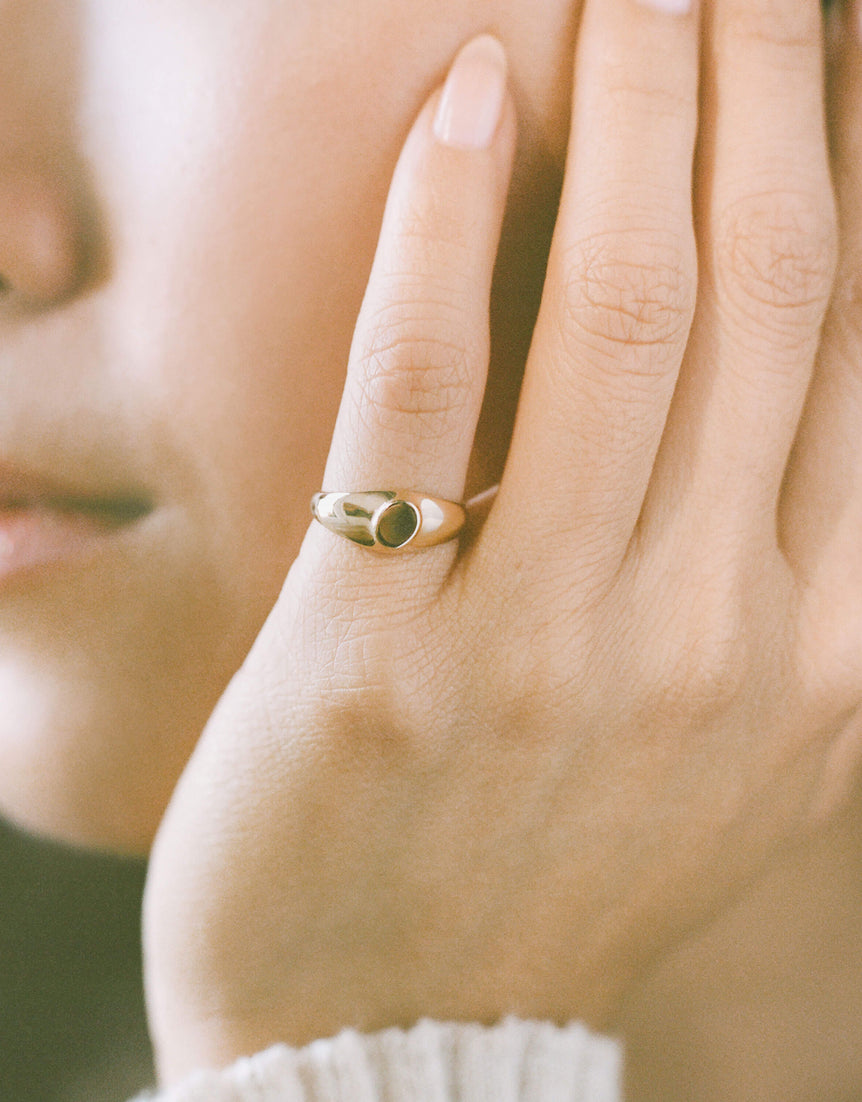 Close-up of a person wearing a dainty gold signet ring on their pinky