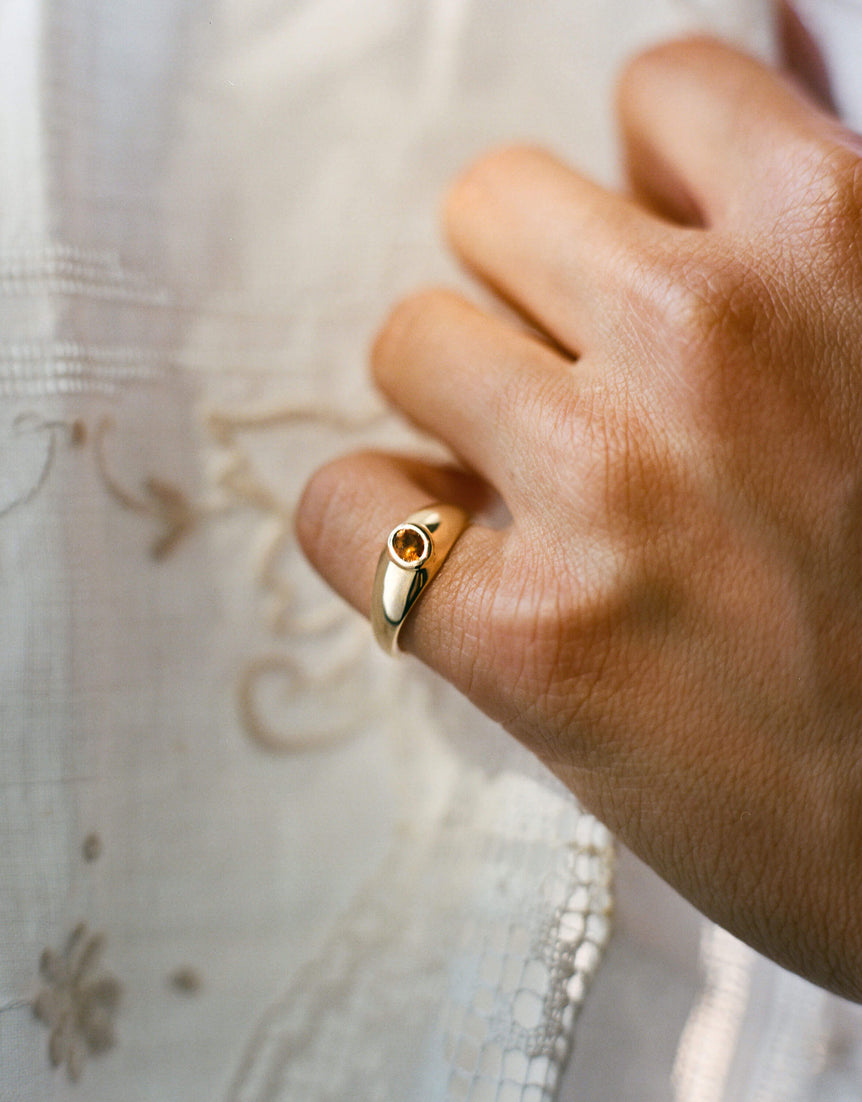 Gold signet ring with an oval citrine gemstone worn on pinky