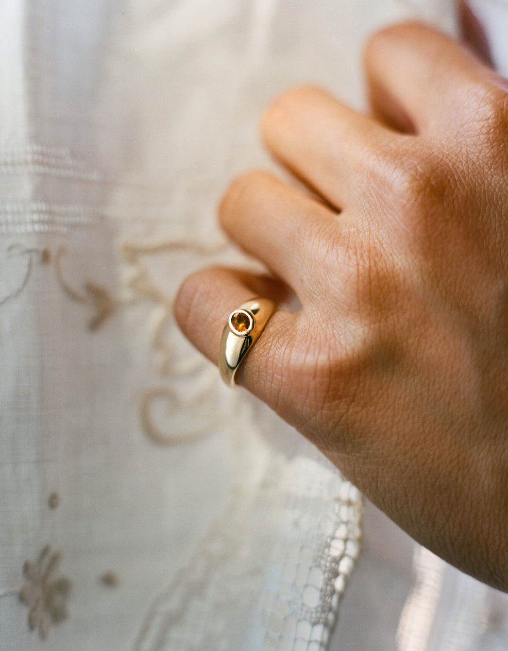 Gold signet ring with an oval citrine gemstone worn on pinky