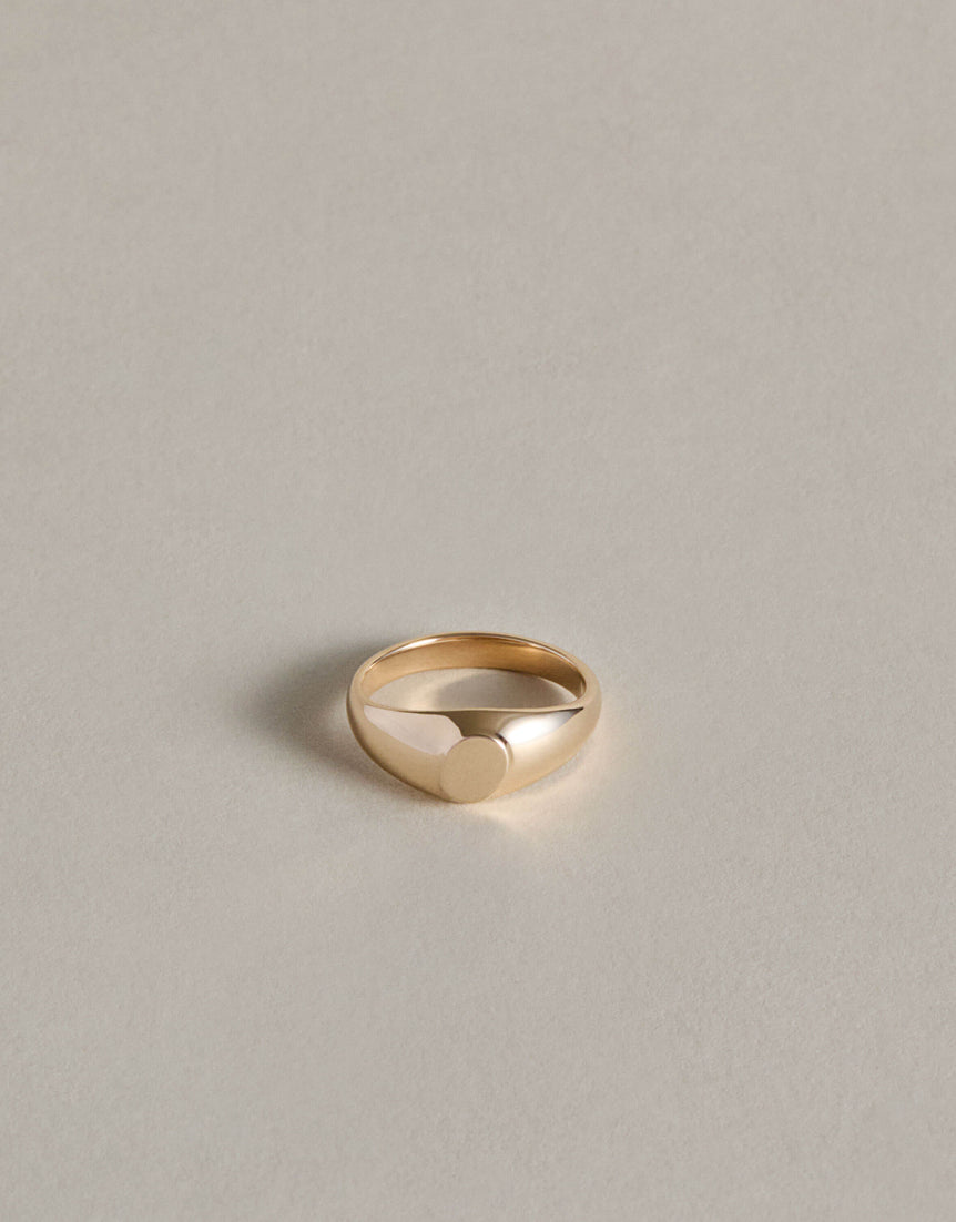 Gold oval signet ring on a light gray background