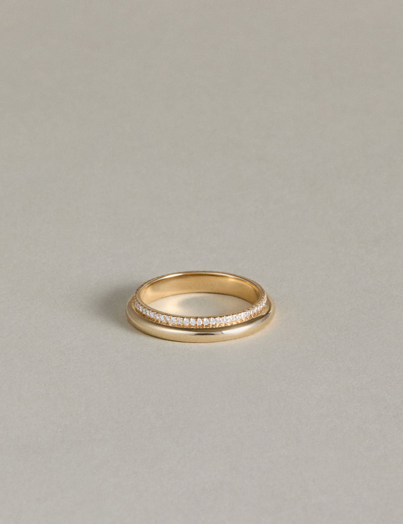Gold ring with an eternity band of pave diamonds on a light gray background