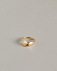 Gold signet ring with an oval citrine gemstone on a light gray background