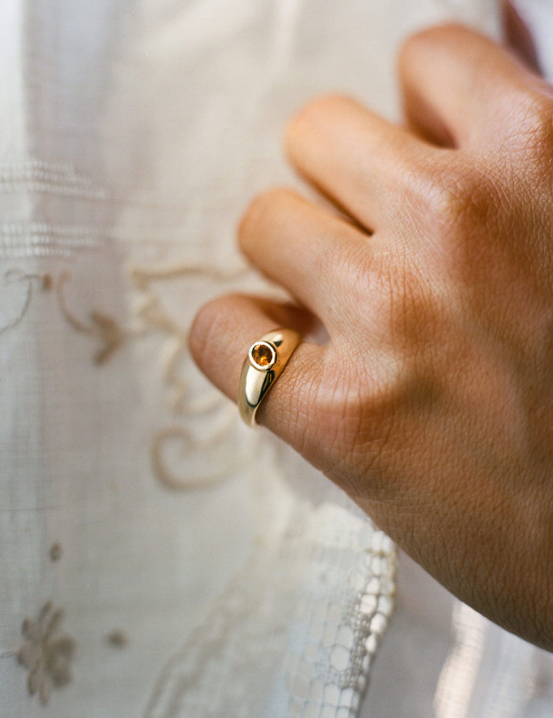 Gold signet ring with an oval citrine gemstone worn on pinky