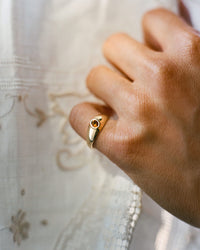 Gold signet ring with an oval citrine gemstone worn on pinky